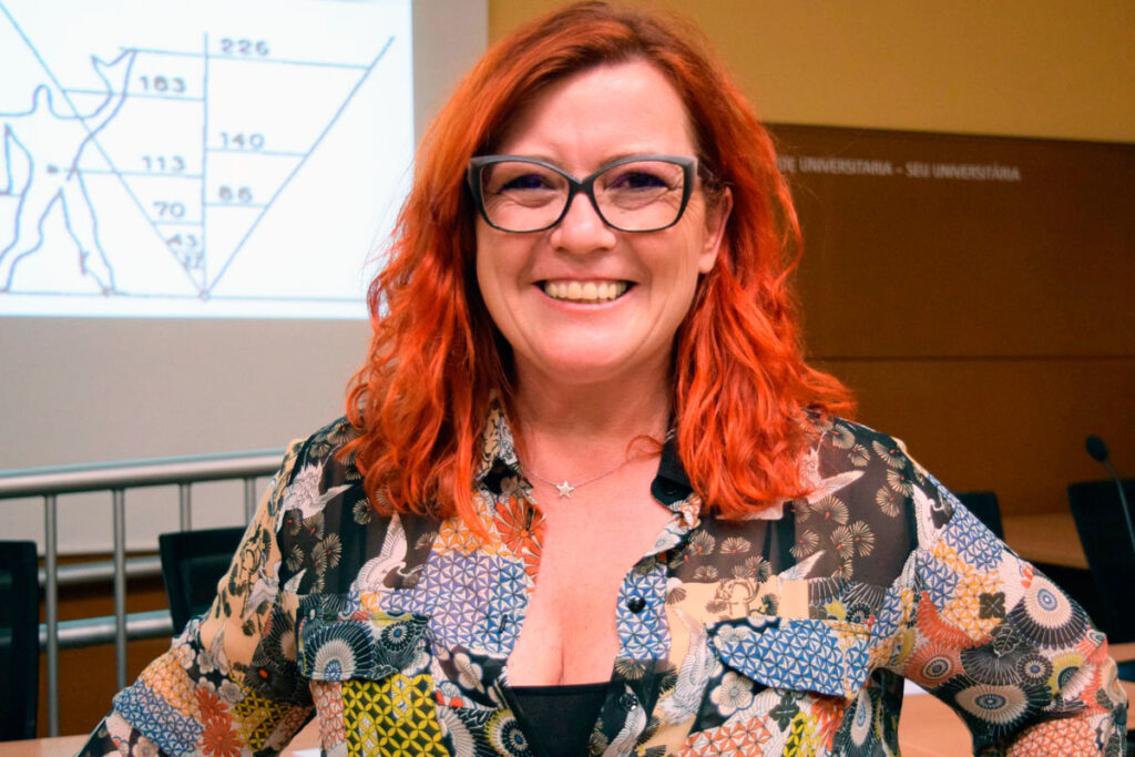 Una mujer sonriendo pelirroja delante de una pizarra en una sala de conferencias